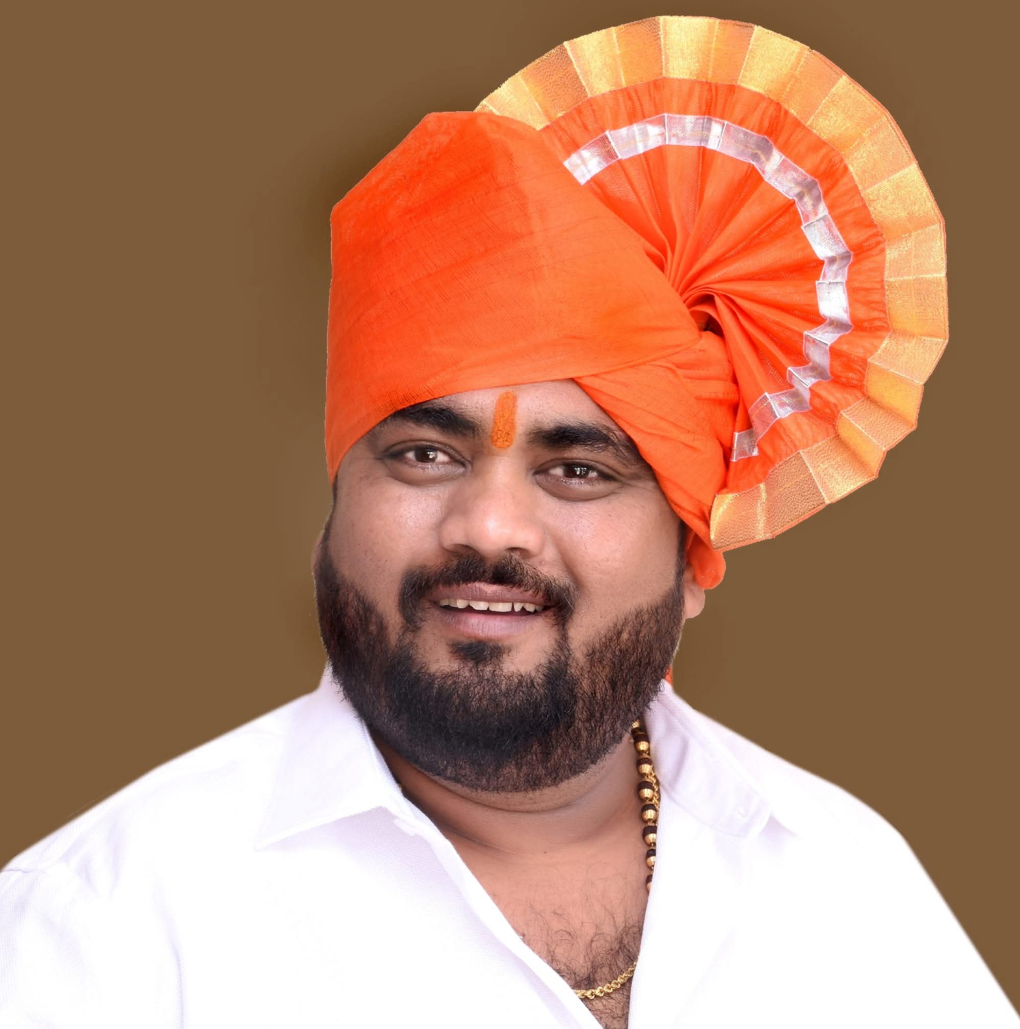 Portrait of Shamkant Kale in a white shirt with an orange ceremonial pagdi.