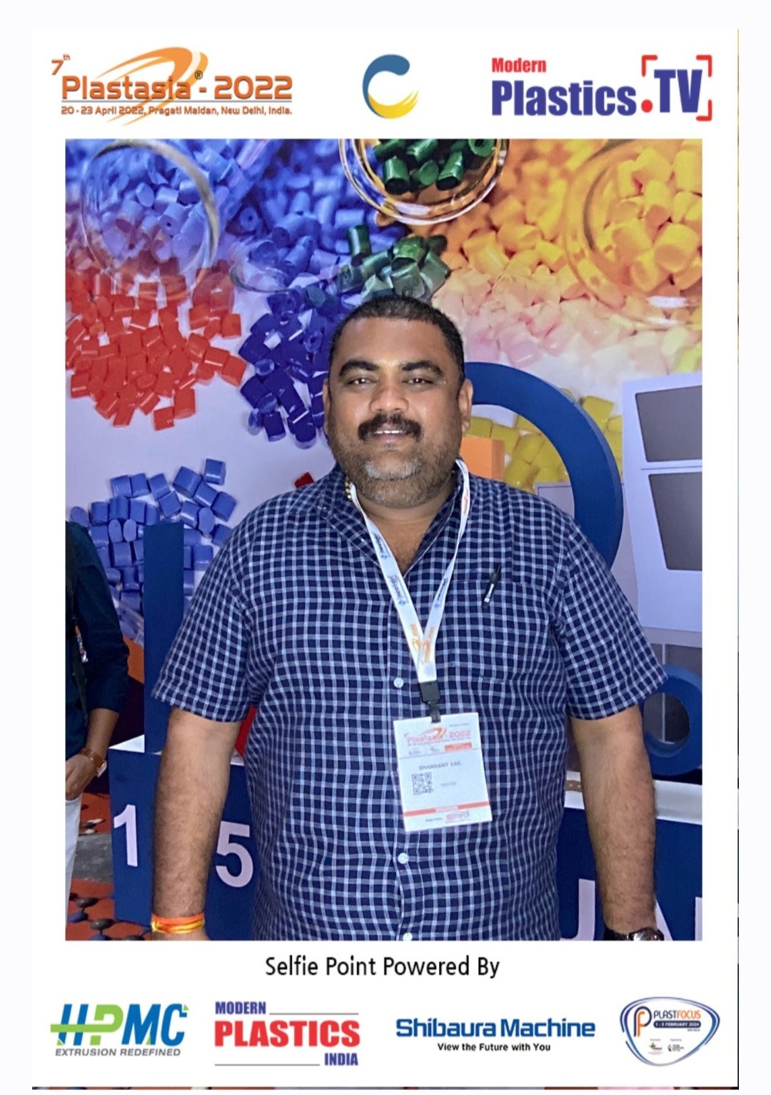 Shamkant Kale at a plastics industry expo with polymer branding in the background.
